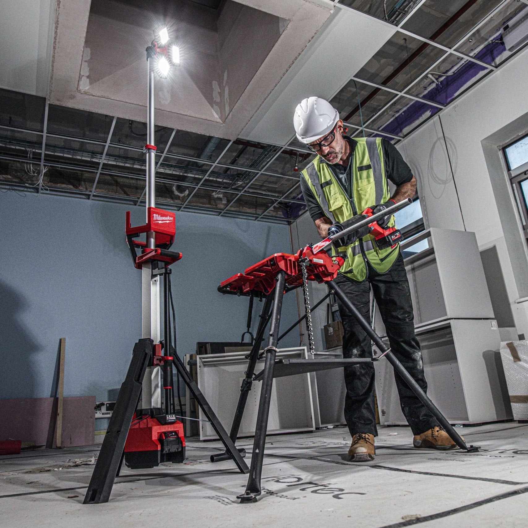 Person using a battery powered tall Milwaukee light in an indoor construction or renovation setting